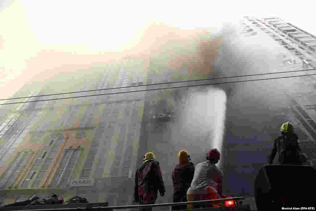 Bangladeshi firefighters try to extinguish a fire that broke out at a high-rise building in Dhaka on March 28. (epa-EFE/Monirul Alam)