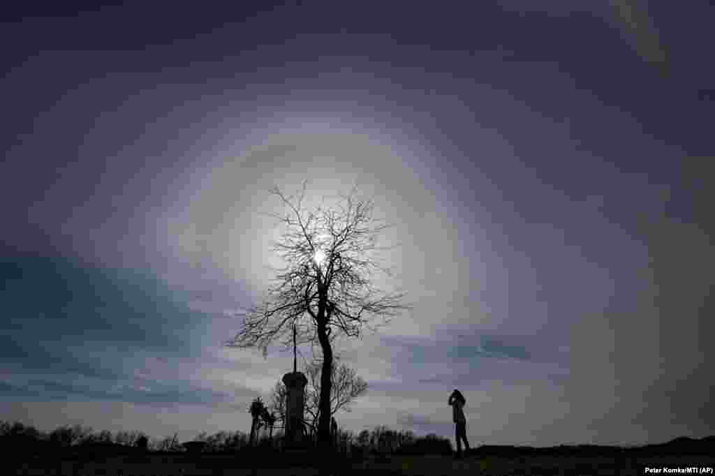 A woman looks at a halo phenomenon around the sun above Salgotarjan, Hungary. The effect is caused by sunlight interacting with ice crystals suspended in the atmosphere. (AP/Peter Komka)