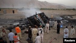 Police and security officials gather near the wreckage of a bus which was hit by a bomb attack in Balochistan.