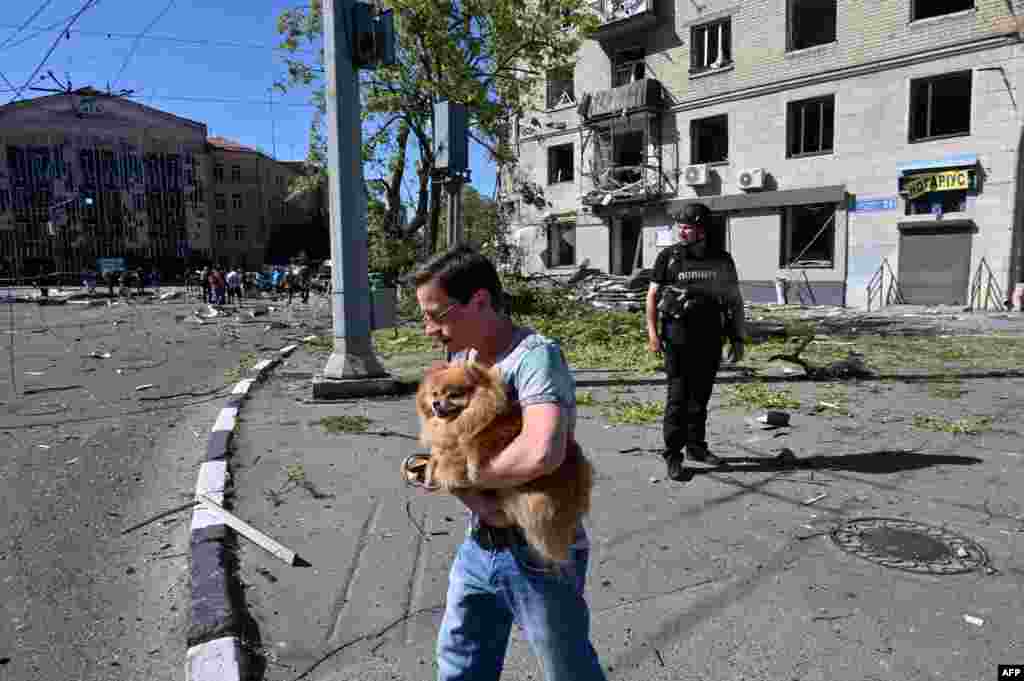 Місцевий житель виносить собаку зі зруйнованого житлового будинку&nbsp;в центрі Харкова після обстрілу військами РФ, 22 червня 2024 року