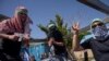 Demonstranți israelieni „deghizați” în luptători palestinieni demonstrează în râsetele mulțimii la 3 aprilie 2024 în fața sediului din Ierusalim al UNRWA, agenția pentru refugiați acuzată fără dovezi că ar fi colaborat cu Hamas. 