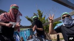 Demonstranți israelieni „deghizați” în luptători palestinieni demonstrează în râsetele mulțimii la 3 aprilie 2024 în fața sediului din Ierusalim al UNRWA, agenția pentru refugiați acuzată fără dovezi că ar fi colaborat cu Hamas. 