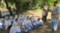 A Security official stands guard as school girls attend their school in open air following the school building destruction by suspected militants, in Tirah valley, in Khyber tribal district. (file photo)