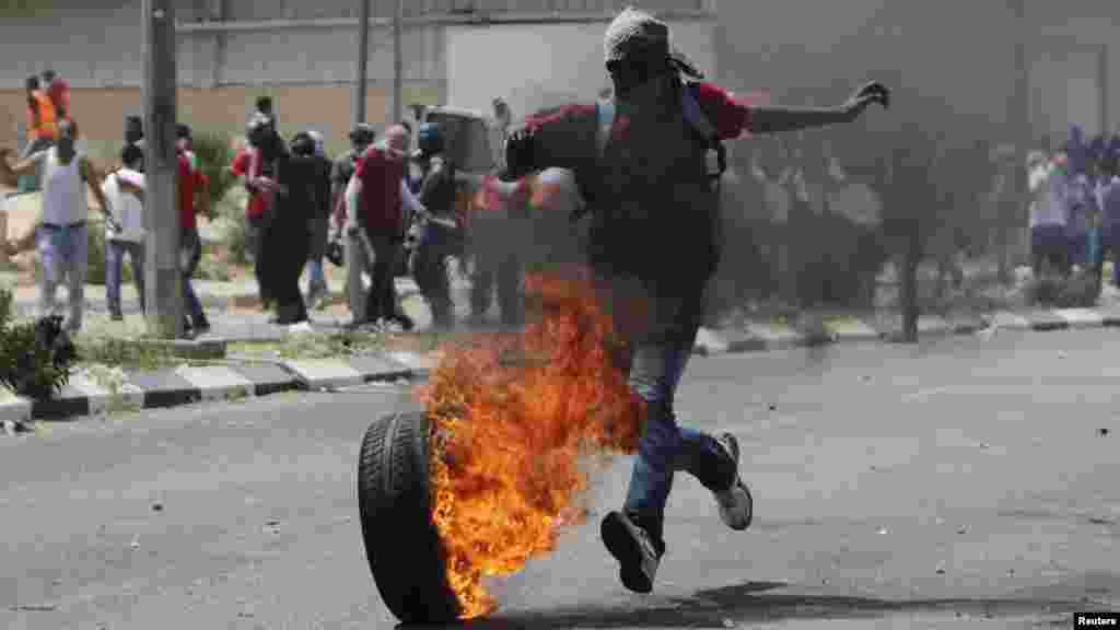 A Palestinian protester kicks a burning tire during clashes between Palestinian stone-throwers and Israeli security forces outside Ofer prison near the West Bank city of Ramallah. (Reuters/Mohamad Torokman)