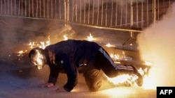 Привърженик на опозицията се опитва да угаси огъня по тялото си, след като коктейл Молотов е хвърлен погрешка върху него по време на протеста в Тирана на 22 декември 2025 г.