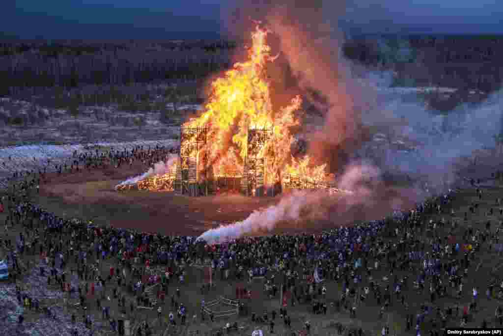 People watch a sculpture of a bridge burning at the Nikola-Lenivets art park about 200 kilometers southwest of Moscow on February 29.