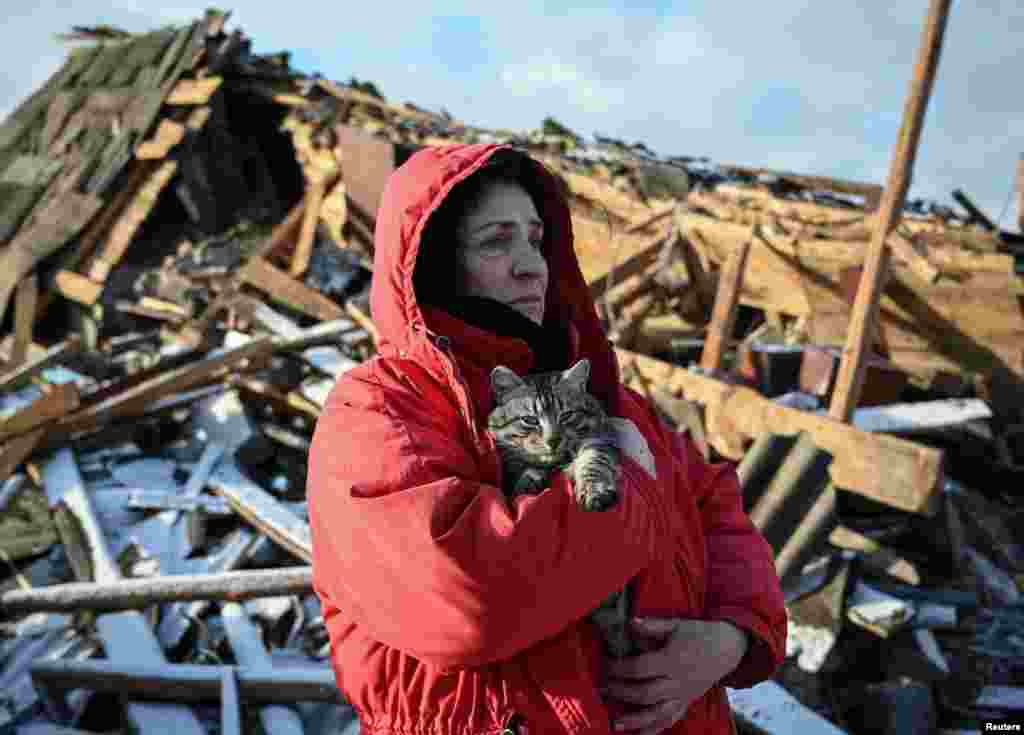 A woman holds her cat as she surveys the ruins of her house, which was destroyed by a Russian missile strike on the northern Ukrainian city of Chernihiv.