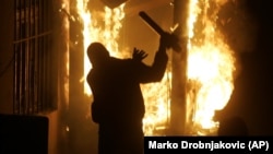 A rioter throws a street sign into the burning U.S. Embassy in Belgrade, Serbia, in February 2008. 