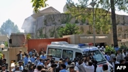 Pakistani security and medical personnel and media gather in front of the UN office in Islamabad after the blast.