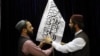 Taliban officials arrange a Taliban flag before the start of the group's press conference on August 17, at which the militants sought to assuage fears that they would reestablish a repressive regime in Afghanistan similar to that of their previous stint in power in 1996-2001. 