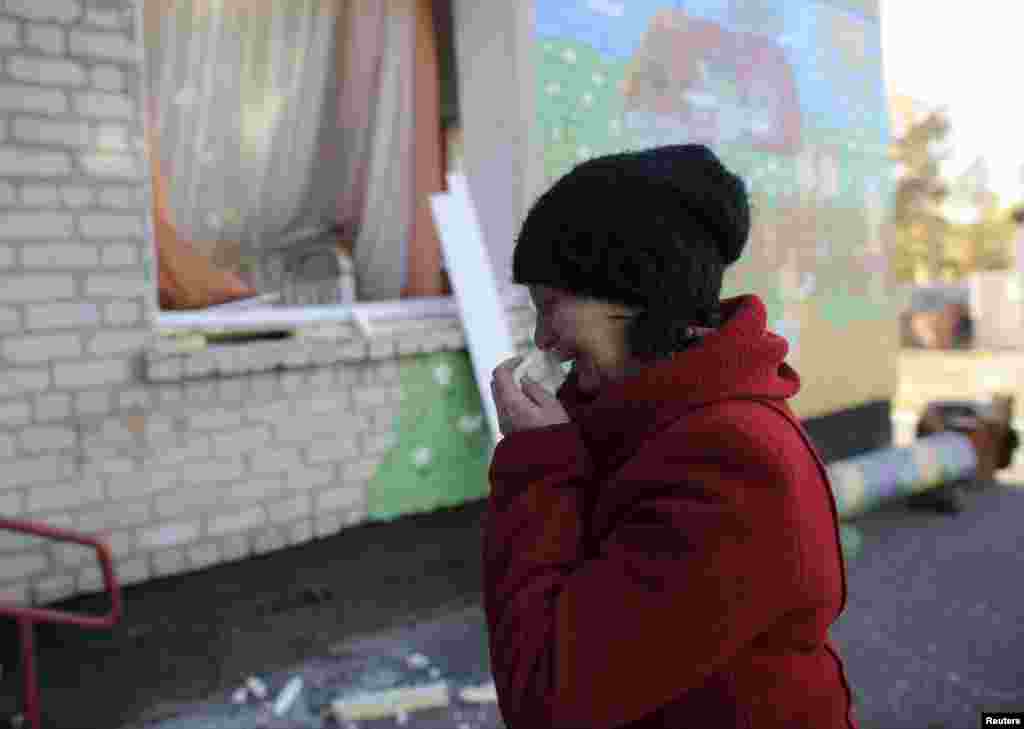Жінка плаче біля будівлі дитсадка, який був пошкоджений в результаті вибухів на військовому складі у Сватові