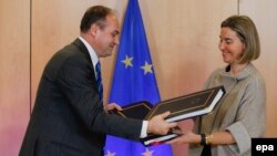 Kosovski šef diplomatije Enver Hodžaj i evropska komesarka Federika Mogerini razmenjuju dokumente posle potpisivanja Sporazuma za učešće Kosova u programima EU, Brisel