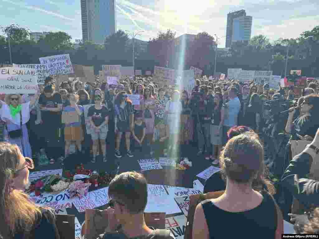 Protestatarii afișează pancarte cu mesaje împotriva violenței asupra femeilor și a blamării victimelor, au aprins lumânări și au adus multe flori pentru Teodora, tânăra de 23 de ani ucisă sâmbâtă într-un cartier de lux de lângă București de cel care a abuzat-o de când avea 14 ani. Teodora era de mână cu fetița ei de 3 ani când a fost omorâtă.