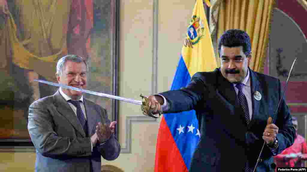 Venezuelan President Nicolas Maduro (right) holds a sword, given as gift by Russian oil company Rosneft CEO Igor Sechin, during the signing of agreements at the Miraflores presidential palace in Caracas on July 28. (AFP/Federico Parra)