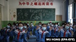 Iskolás gyerekek énekelnek egy külföldi újságíróknak a kormány által szervezett kiránduláson a kínai Kasgarban 2021 áprilisában