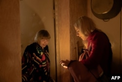 Аліна Дяченко, членкиня гуманітарної організації «Старенькі», дає світло 77-річній пенсіонерці Ніні Сидоренко в Києві під час масових блекаутів після російських обстрілів енергетичної інфраструктури України. Січень 2026 року