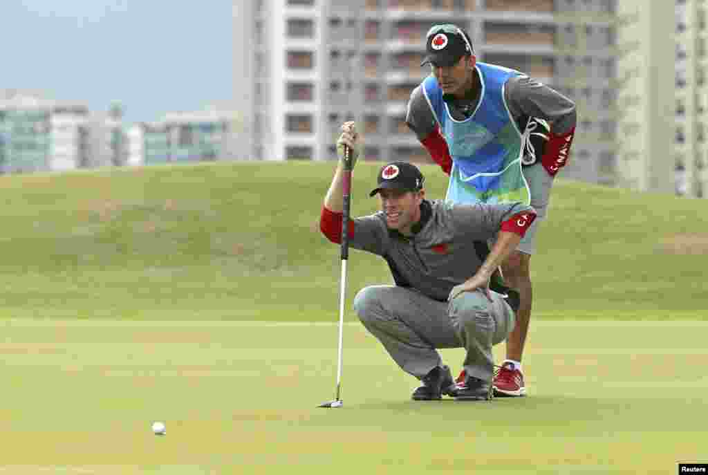 David Hearn of Canada lines up a putt with his caddie Ralph Bower on the first green during the second round of men&#39;s golf preliminary round.