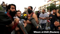 Demonstrators carry a man affected by tear gas during a protest in Baghdad on October 25.