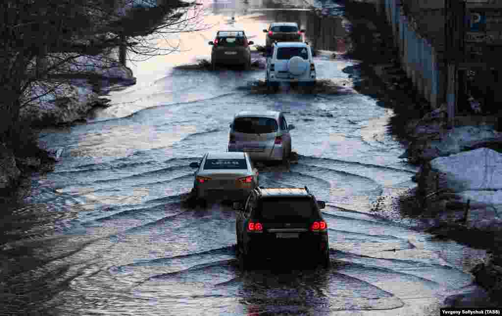 Vehicles drive along a street in the Russian city of Omsk that has been flooded by melting snow. (TASS/Yevgeny Sofiychuk)