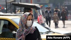 Iranians wear masks to help guard against dangerous levels of air pollution as they walk in the center of the smog-filled capital Tehran, November 13, 2019