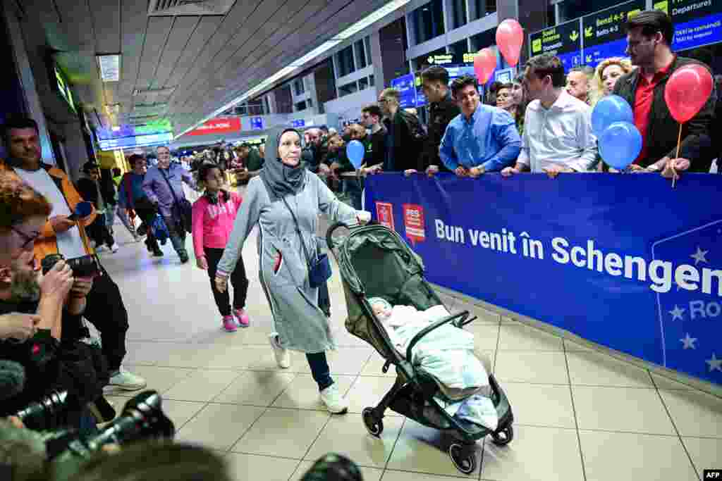 Travelers walk next to a banner reading &quot;Welcome to Schengen!&quot; in Romanian a few minutes after midnight, just after Romania&#39;s official entry into the European area of visa-free travel at Otopeni airport. Bulgaria and Romania joined Europe&#39;s vast Schengen Area of free movement on March 31, opening up travel by air and sea without border checks after a 13-year wait.