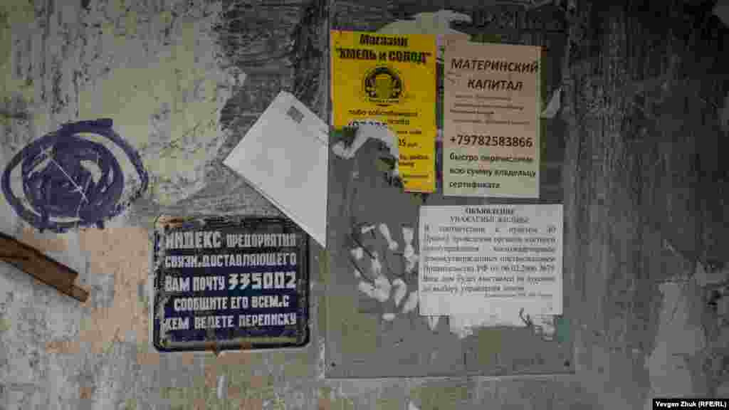 На вході до під&#39;їзду табличка з радянським поштовим індексом, вцілілі позаторішні оголошення і квитанції за комуналку