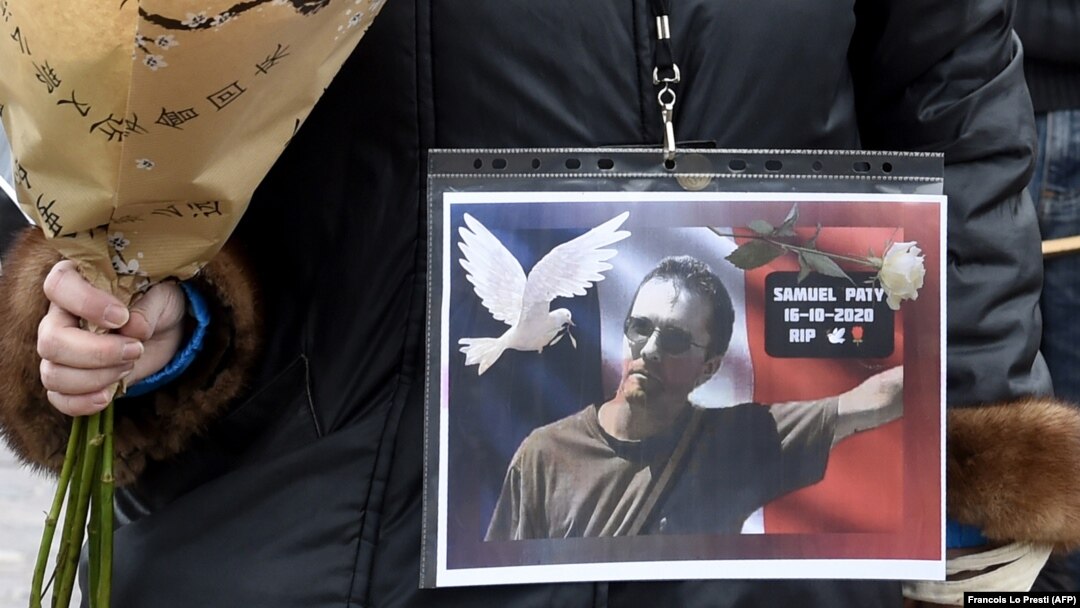 A woman holds a picture of Samuel Paty at a rally in Lille on October 18, 2020, two days after he was beheaded by an attacker who was shot dead by policemen.