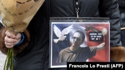A woman holds a picture of Samuel Paty at a rally in Lille on October 18, 2020, two days after he was beheaded by an attacker who was shot dead by policemen.