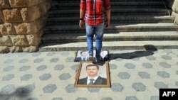 Во центарот на Алепо, момче гази по портретите на Асад. 