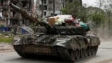 UKRAINE – Service members of pro-Russian troops drive a tank along a street past a destroyed residential building during Ukraine-Russia conflict in the town of Popasna in the Luhansk Region, May 26, 2022