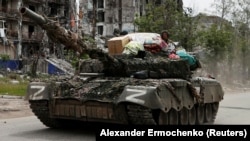 Российские солдаты на танке в городе Попасная в Луганской области с бытовыми вещами, которые, по словам вынужденной переселенки Алины Коренюк, были похищены из её дома. Попасная, 26 мая 2022 года