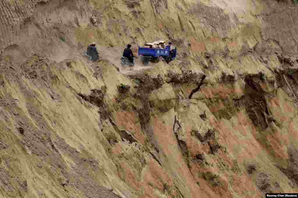 Motorcycles and a truck travel on a road near a cliff at a landslide site after a 6.6-magnitude earthquake hit China's Gansu Province. The death toll from two earthquakes in the province has climbed to 95. (Reuters/Rooney Chen)
