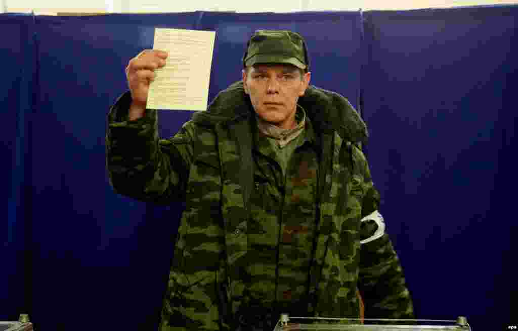 A member of the pro-Russian &quot;self-defense&quot; forces that emerged in Crimea alongside the Russian occupation shows his ballot at a polling station.