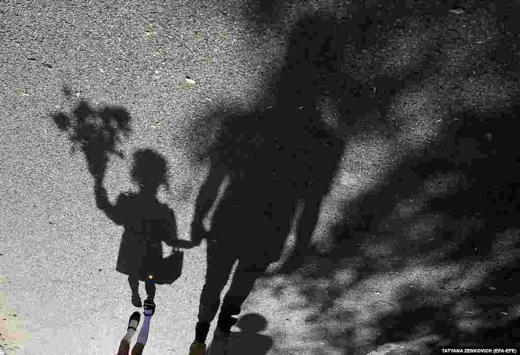 Polina (left), a 6-year-old Belarusian first-grade schoolgirl, and her father cast shadows on the street while on their way to Polina&#39;s first day of schoolon September 2. (epa-EFE/Tatyana Zenkovich)