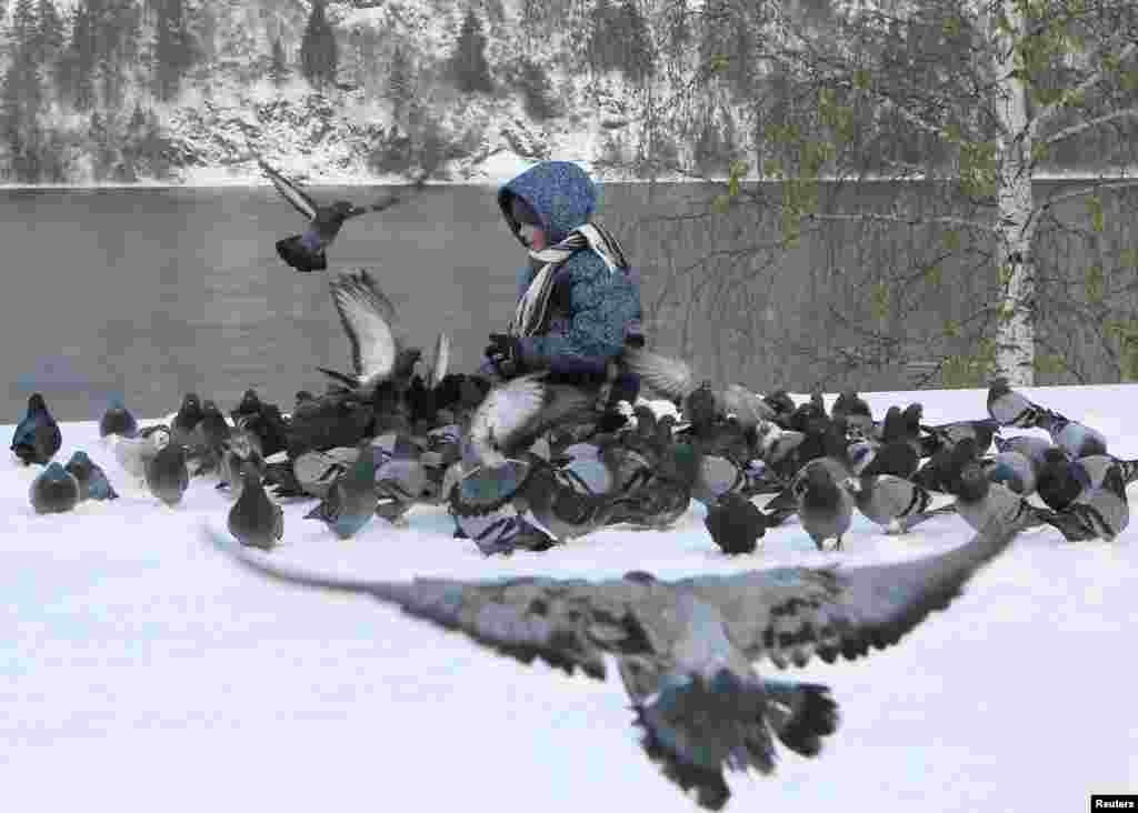 A boy feeds pigeons on a snow-covered embankment of the Yenisei River in the Siberian town of Divnogorsk, Russia. (Reuters/Ilya Naumushin)