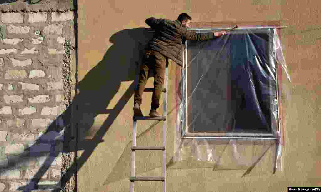 Житель ремонтирует окно своей квартиры. 24 ноября 2020 года.