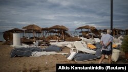 A man looks at damaged umbrellas and lounge chairs following heavy storms in the village of Nea Plagia in northern Greece. 