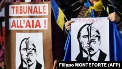 Женщины держат плакаты с надписью «Международный уголовный суд в Гааге» над портретами Владимира Путина и Александра Лукашенко во время демонстрации в поддержку Украины. Рим, 24 февраля 2022 года