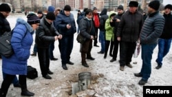 People look at the remains of a rocket that hit a residential street in the eastern town of Kramatorsk on February 10.