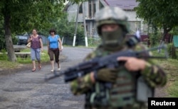 Women walk toward a Ukrainian government soldier searching for members of Right Sector in the village of Bobovyshche, near Mukacheve, on July 13.