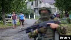 Women walk toward a Ukrainian government soldier searching for members of Right Sector in the village of Bobovyshche, near Mukacheve, on July 13.