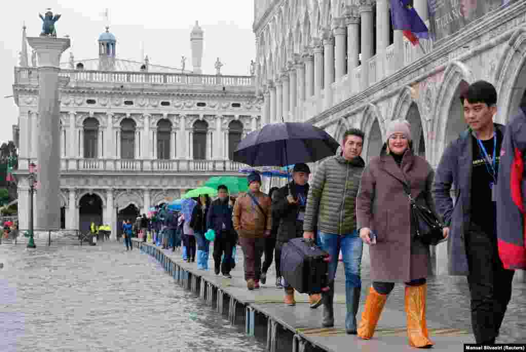 Туристи та венеціанці пересуваються вулицями по спеціально збудованих містках