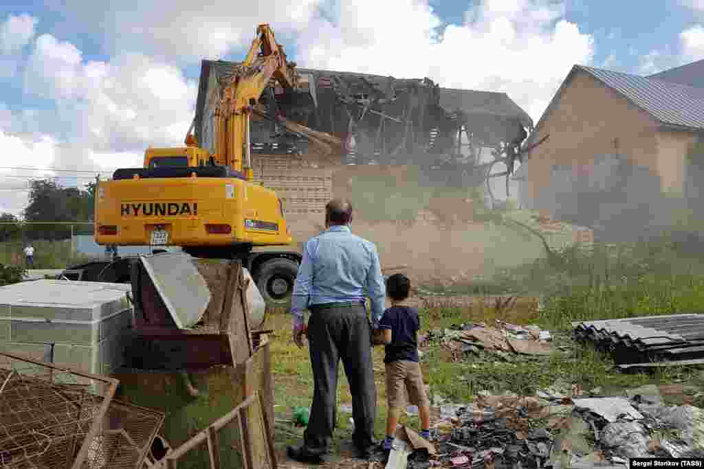 Një burrë dhe një djalë e shikojnë rrënimin e shtëpive rome, të ndërtuara paligjshëm në fshatin Plekhanovo në rajonin Tula të Rusisë.&nbsp;