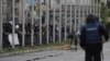 A mourner lights a candle for the victims of the Smiljkovci murders as security forces look on in Skopje on April 16.