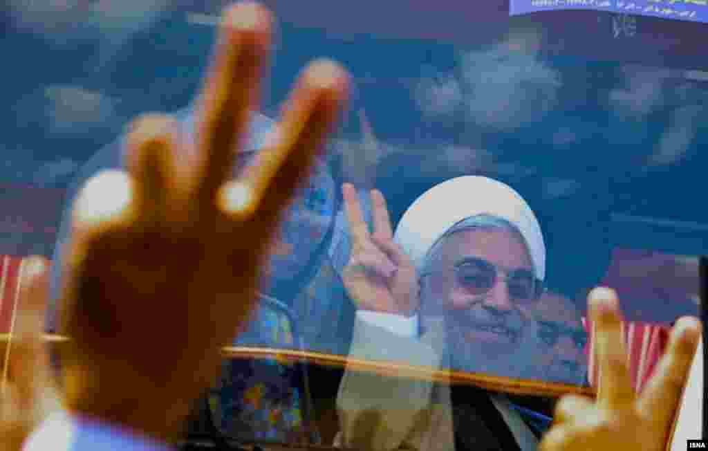 Rohani is seen behind protective glass as he greets supporters.