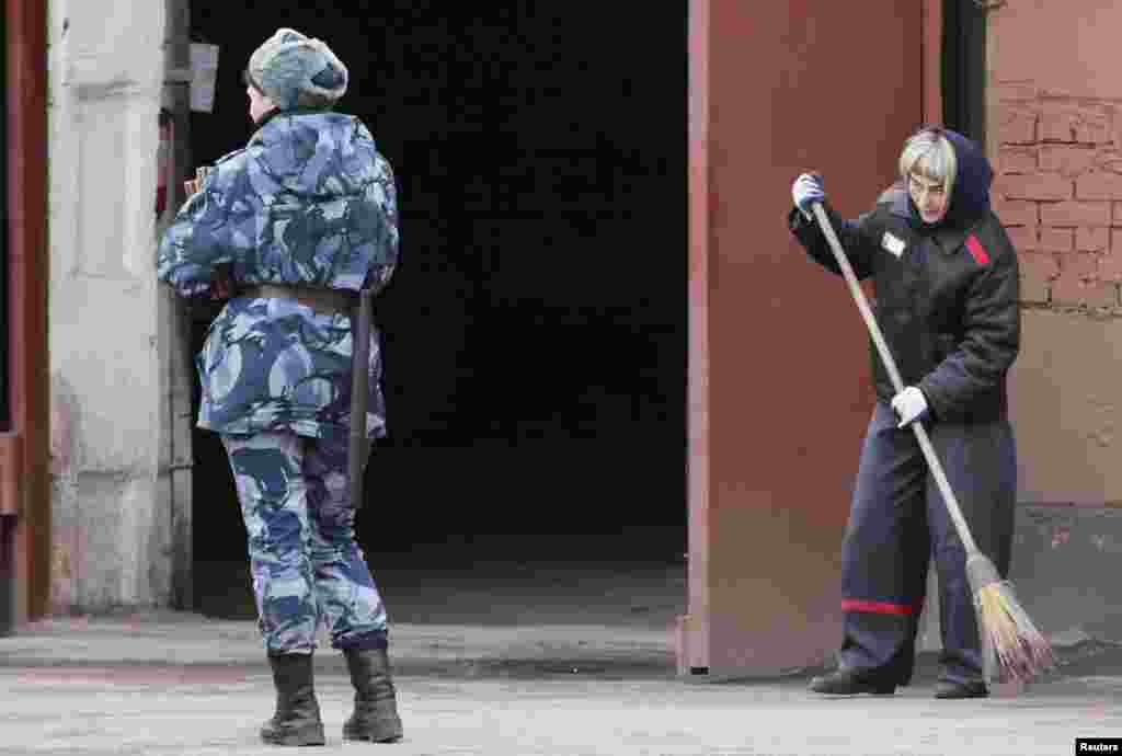 A prison officer stands guard as an inmate sweeps the ground inside female prison camp Number 22 in the Siberian city of Krasnoyarsk, Russia, on November 21. (Reuters/Ilya Naymushin)