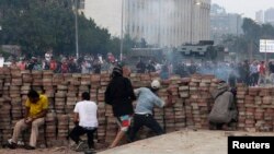 Supporters of deposed Egyptian President Muhammad Morsi throw stones from behind a makeshift barricade they built as they take cover from the police during clashes in Nasr city area, east of Cairo on July 27.