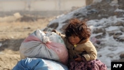 An Afghan girl sits next to aid for her family in Kabul.