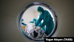 Науқасты компьютерлік томографиядан өткізіп жатқан медицина қызметкері. Көрнекі сурет.