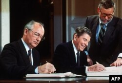 Mihail Gorbaciov (stânga) și Ronald Reagan (dreapta), la Washington, semnând, pe 8 decembrie 1987, tratatul de eliminare a rachetelor nucleare cu rază medie și scurtă de acțiune din arsenalul celor două țări